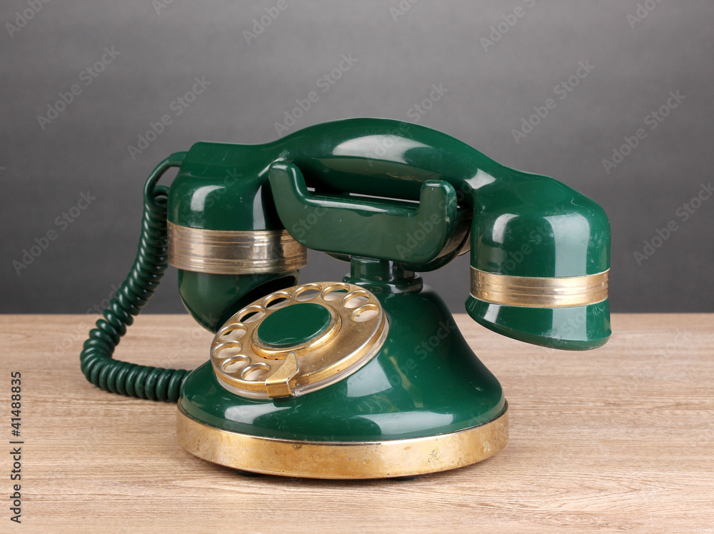 Retro phone on wooden table on grey background