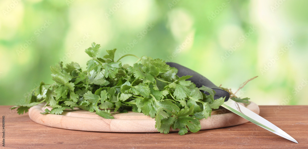 Coriander on a cutting board with knife on green background