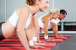 © michaeljung - group of fitness people doing pushups in gym