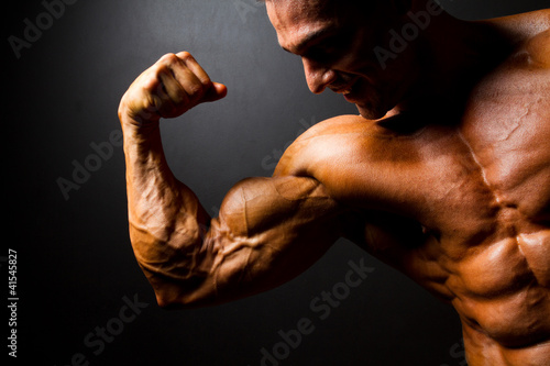 Fotomural strong bodybuilder posing on black background