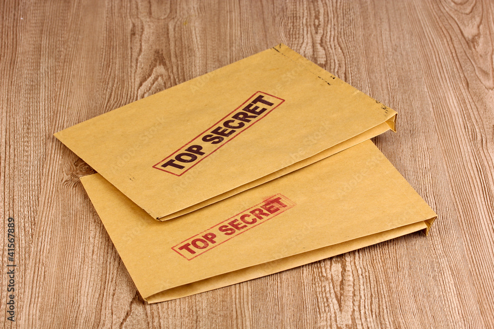 Envelopes with top secret stamp on wooden background