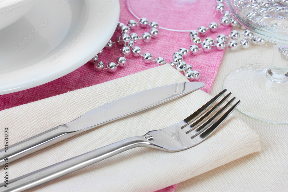 Table setting with fork, knife, plates, beads and napkin