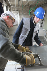 Two manual workers cutting sheet metal