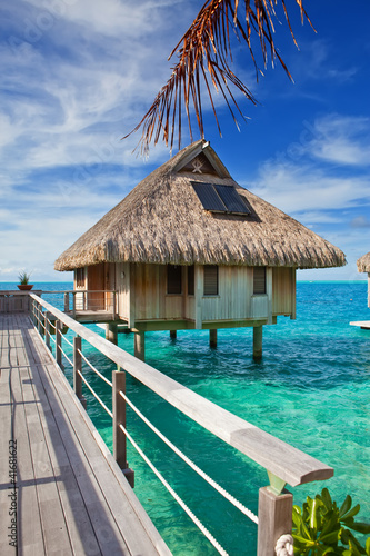 Fototapeta na wymiar The wooden bridge to a hut over water at the ocean