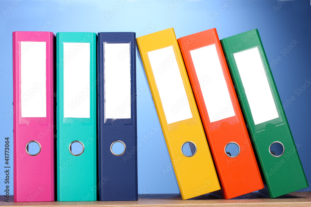 bright office folders on wooden table on blue background