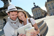 © goodluz - Couple standing by the Place de la Bourse with electronic tablet
