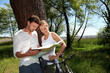 © goodluz - Couple on a bike ride making a stop to look at map