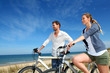 © goodluz - Couple standing on a sand dune with bicycles