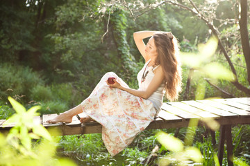 young woman sitting on the bridge in the forest