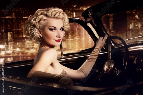 Naklejka dekoracyjna Woman in retro car against night city.