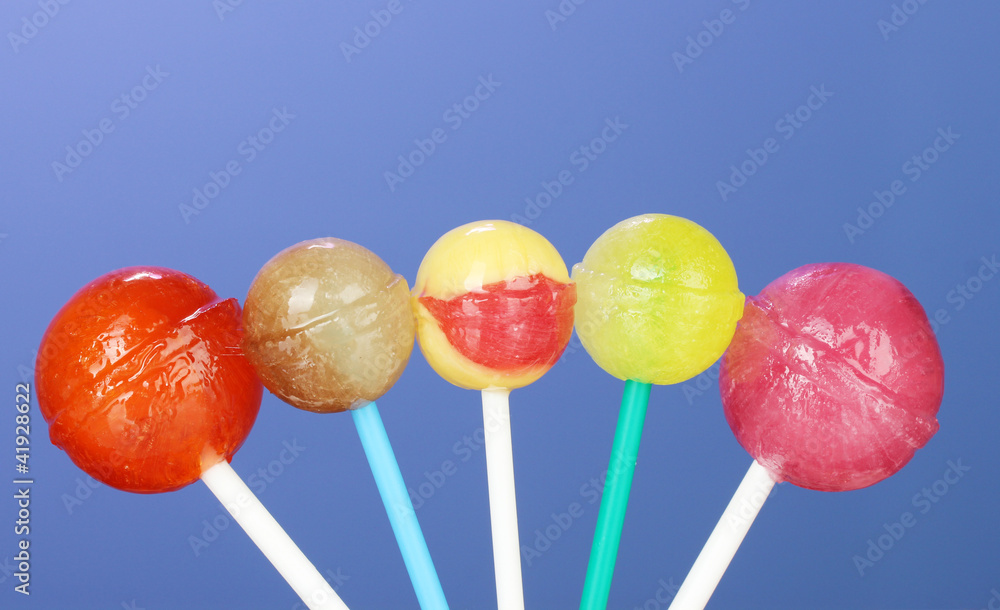 Bright and delicious lollipops on dark blue background close-up