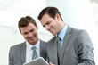 © goodluz - Business partners working in hallway with electronic tablet