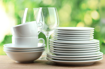 Clean dishes on wooden table on green background