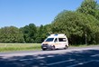Weißer Krankenwagen auf Landstraße mit Wiesen und Wald, Niedersachsen, Deutschland, Europa