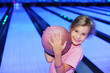 Smiling little girl holds ball in bowling club