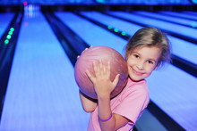 Smiling Little Girl Holds Ball In Bowling Club