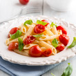 Penne pasta with cherry tomatoes and basil on a plate