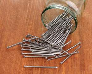 Wall Mural - Metal nails and glass jar on wooden background