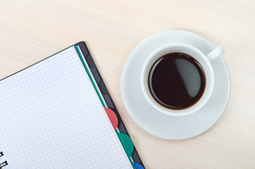 Coffee cup with note book on table