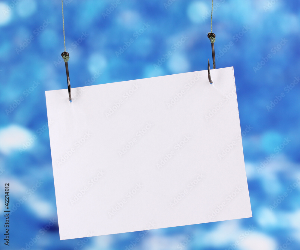 Empty sheet of a paper on fish hooks on blue background
