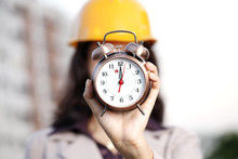Cheerful Female Construction Engineer Holding Alarm Clock