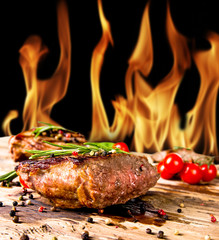 Wall Mural - Grilled beef steaks with flames on background