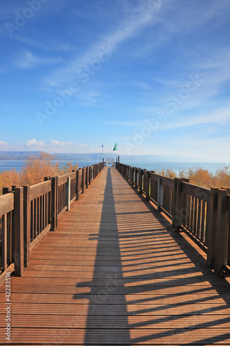 Board z aluminiowym obramowaniem Długie drewniane molo nad jeziorem kinneret