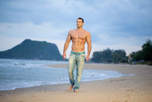 Muscular Male Walking Along A Beach