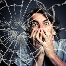 Scared Adult Man With Hand Covering Mouth And Broken Glass.