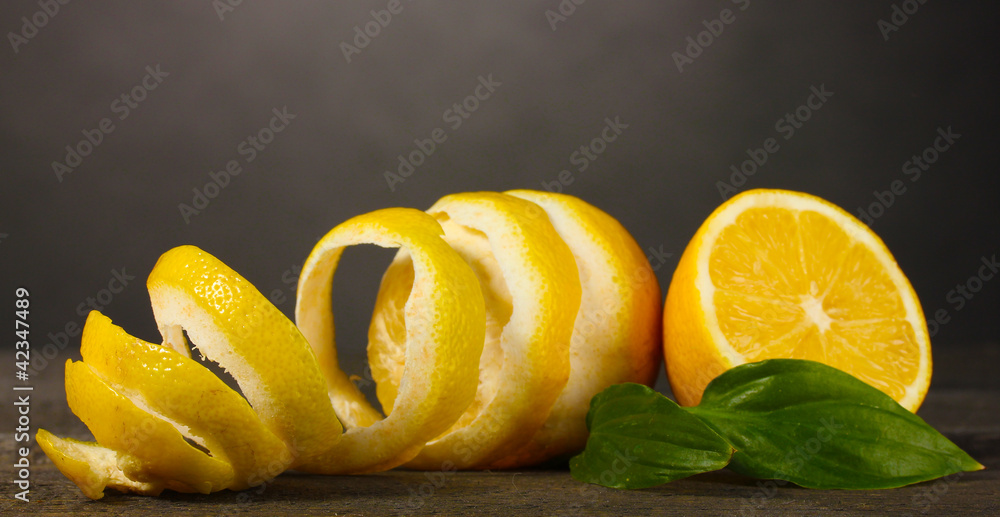ripe lemons with leaves on wooden table on grey background