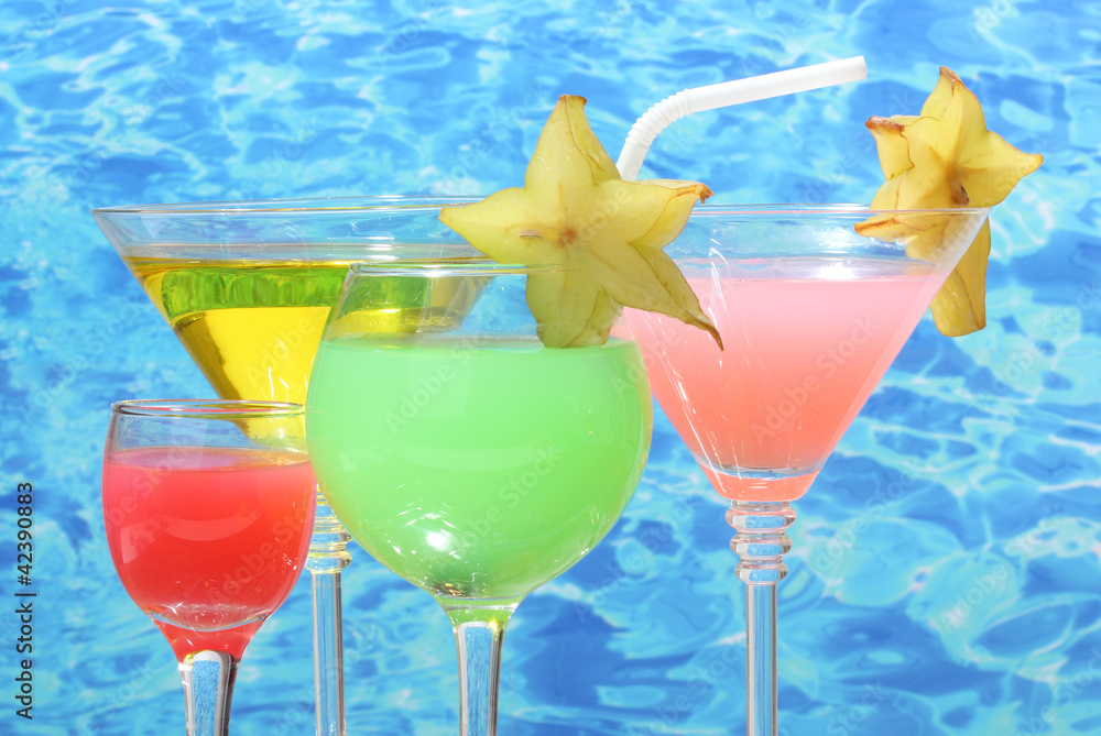 Glasses of cocktails on table on blue sea background