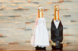 Two bottles of champagne in bride and groom clothes in table