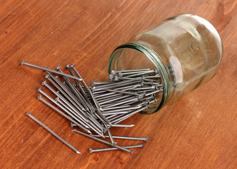 Wall Mural - Metal nails and glass jar on wooden background