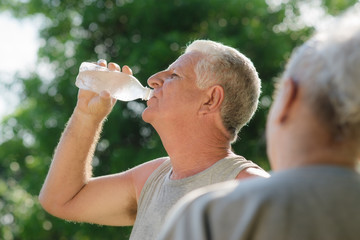 Seniors drinking water after fitness in park