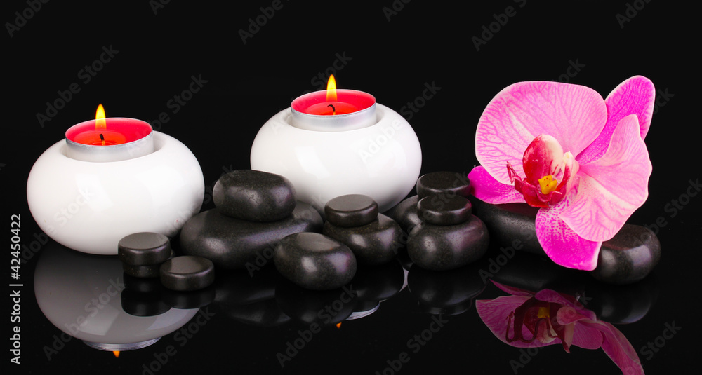 Spa stones with orchid flower and candles isolated on black