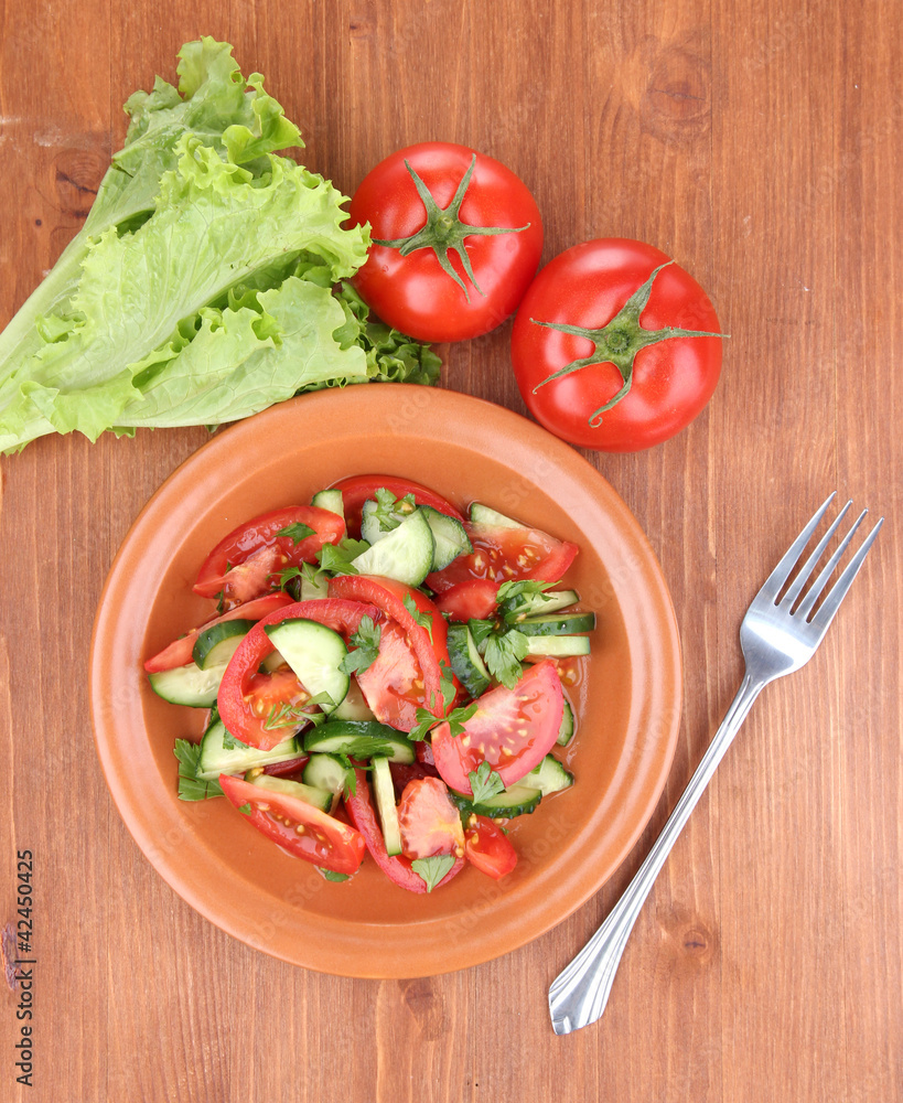 Fresh salad with tomatoes and cucumbers on wooden background
