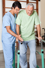 Therapist Assisting Senior Man To Walk With The Support Of Bars