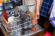 Hausfrau beim Geschirr abwaschen mit Geschirrspüler