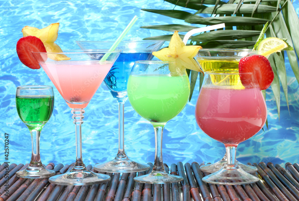 Glasses of cocktails on table on blue sea background