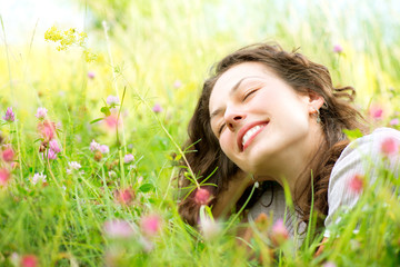 Wall Mural - beautiful young woman lying in meadow of flowers. enjoy nature