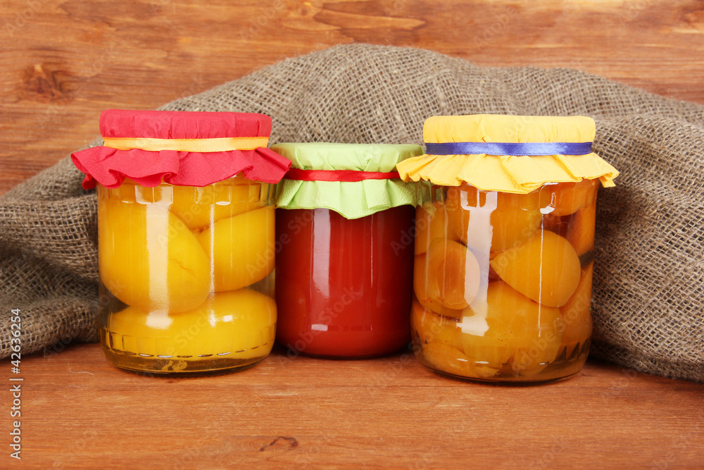Jars with canned fruit on wooden background close-up