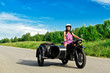 Pretty woman riding a motorcycle with a sidecar.