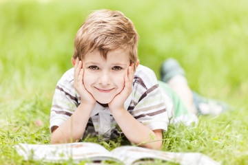 Beauty smiling child boy reading book outdoor