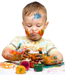 Little boy is playing with paints