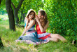 © stormy - Two happy girl friends sitting in green park and talking