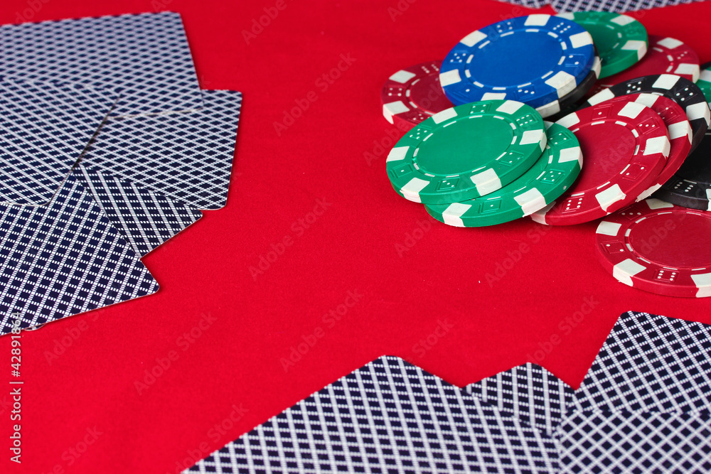 poker chips and playing cards on a red table