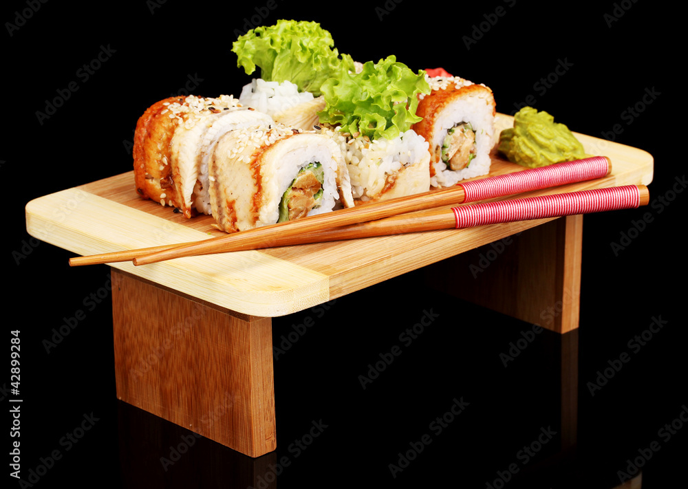Tasty rolls served on wooden plate isolated on black