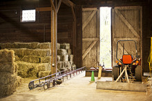 Barn Interior With Hay Bales And Farm Equipment