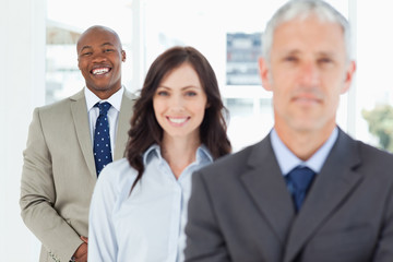 Young smiling employee standing upright and following his team