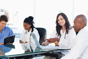 Two smiling medical interns working at the computer near colleag